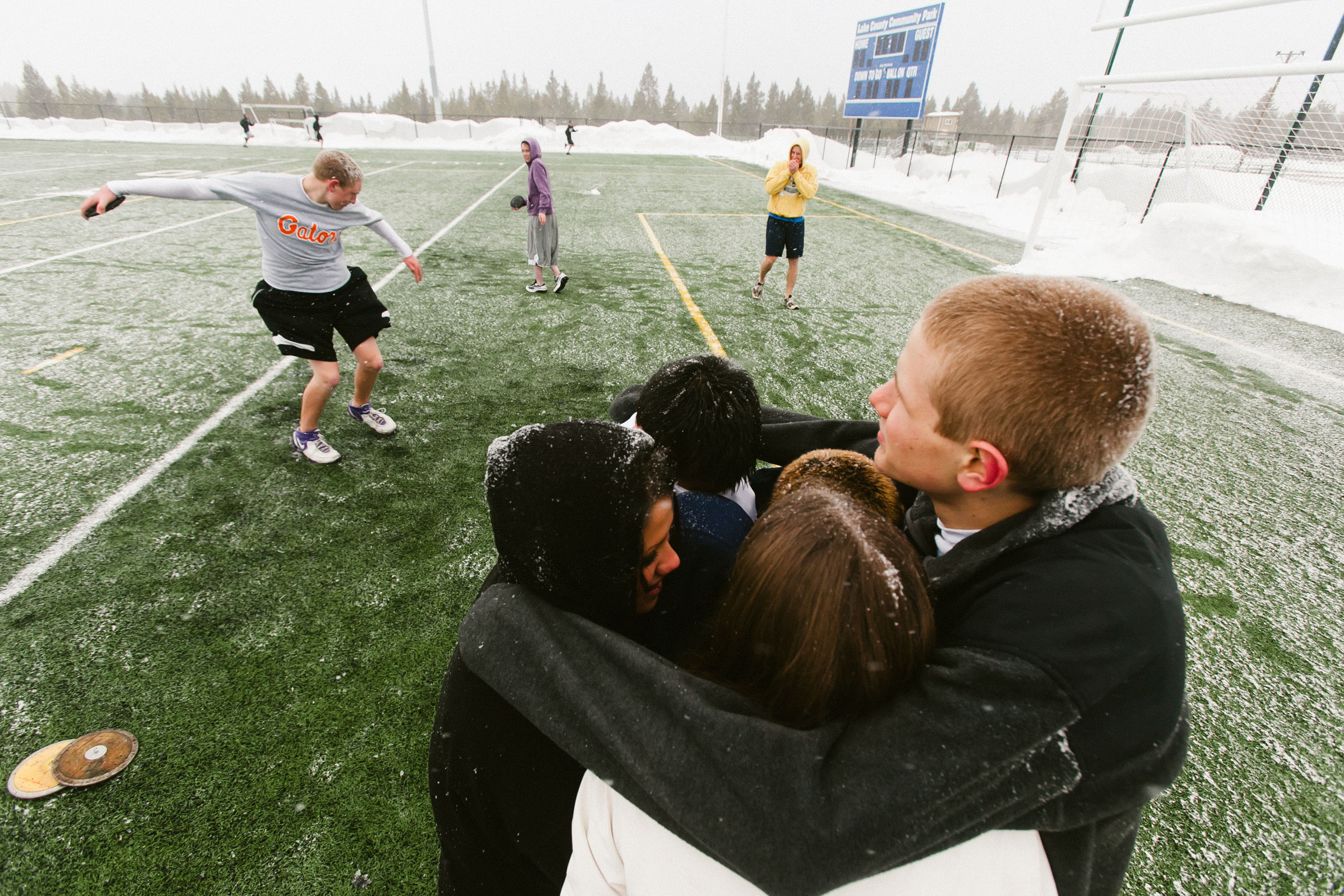 teenagers huddle together to stay warm as track practice resumes